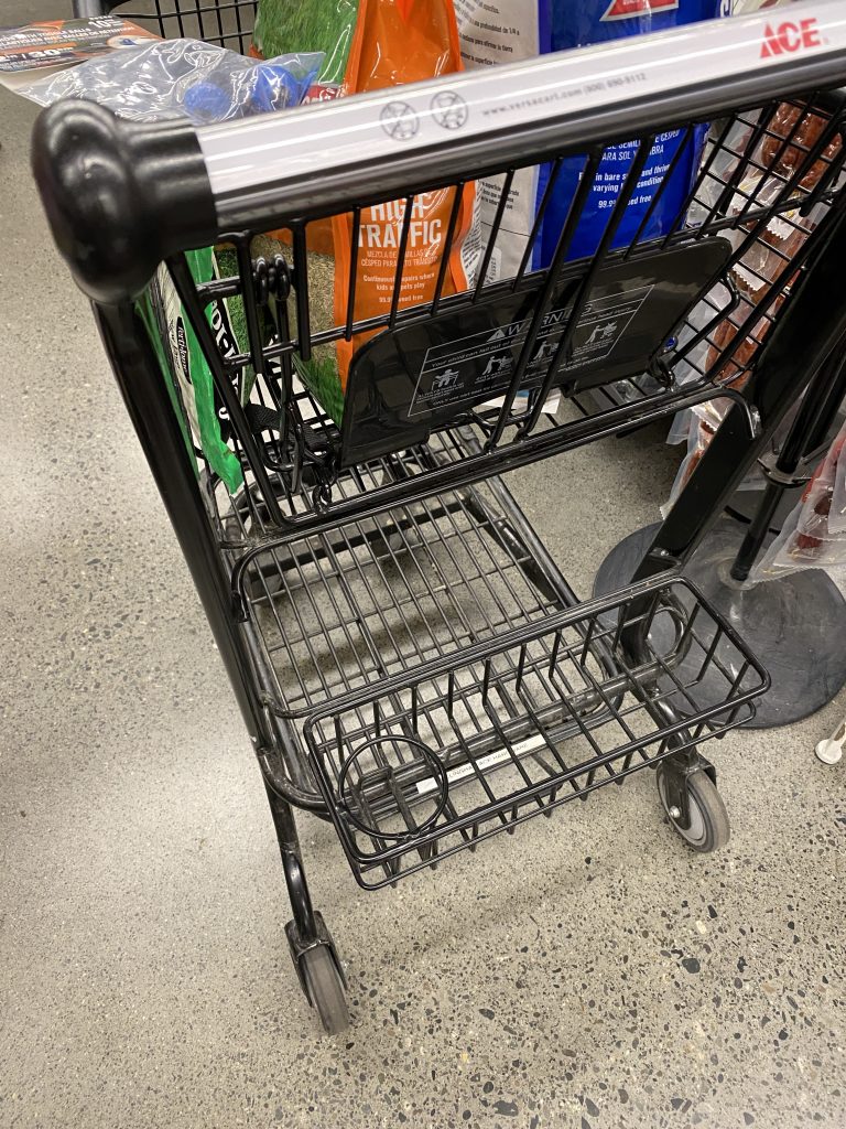 Photo of a shopping cart showing the cupholder at the bottom of the cart, near the wheels.